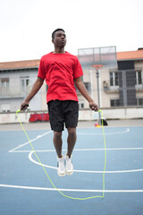 Fototapeta premium African young basketball player skipping rope to warm up