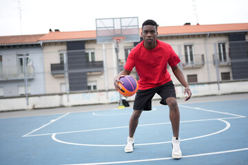 Obraz premium African basketball player dribbling in an outdoor court