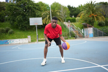 Fototapeta premium African man dribbling a basketball ball at the outdoor courtyard
