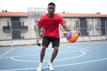 African basketball player dribbling in an outdoor basketball court