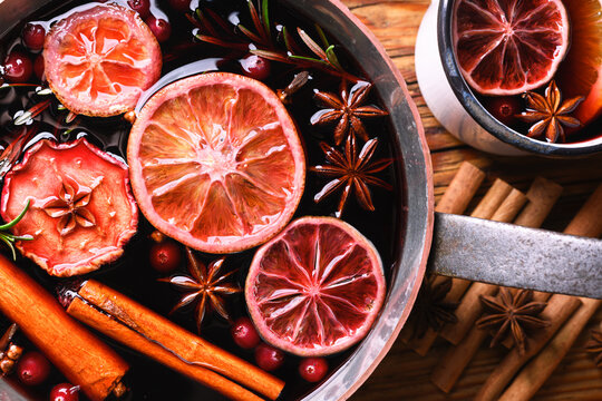 Close up of copper pot with red mulled wine with slices of orange, apple, cinnamon, star anise, rosemary and cranberries. Food photography