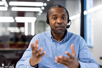 Businessman using headset participates in video call discussing projects. Focused expression...