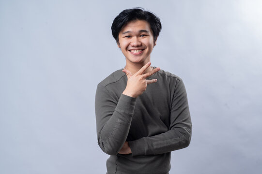 Portrait of an Asian person wearing a long-sleeved gray shirt, showing a specific number with their fingers, isolated against a white background.