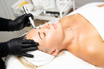 Microneedle RF lifting procedure. A cosmetologist performs a facial rejuvenation procedure on a...