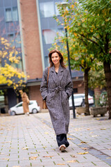 Fototapeta premium Attractive mid aged woman walking outdoors in city street on autumn day