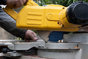 Carpenter cuts a slat at an angle with a circular cross-cut saw, ideal for indoor construction with cutting line display