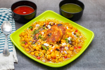 Dabeli is a spicy Indian street food made with a potato filling, tamarind chutney, and sev, served in a bun.