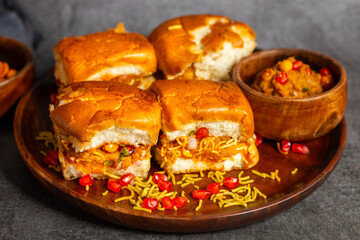 Dabeli is a spicy Indian street food made with a potato filling, tamarind chutney, and sev, served in a bun.