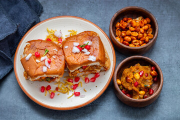 Dabeli is a spicy Indian street food made with a potato filling, tamarind chutney, and sev, served in a bun.