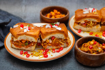Dabeli is a spicy Indian street food made with a potato filling, tamarind chutney, and sev, served in a bun.