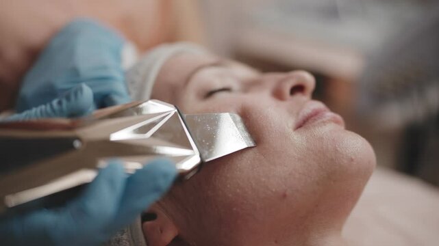 Close-up of a woman receiving a galvanic facial treatment at a professional beauty spa for skin rejuvenation.