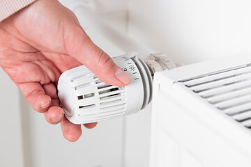 A woman turns up the temperature on a heating radiator as the cold weather sets in