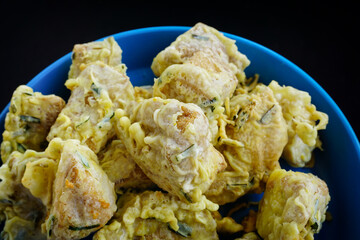 A close-up view shows delicious Indonesian fried tofu Sumpel pieces with green onion batter in a blue bowl ready to eat.