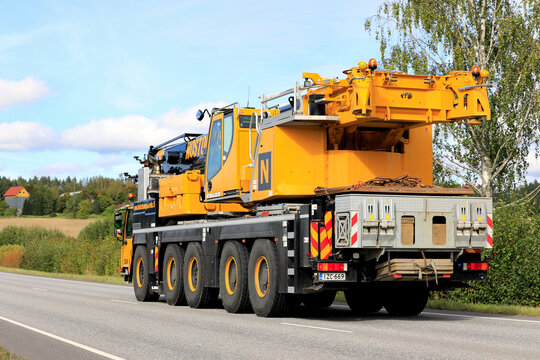 Liebherr LTM 5-axle mobile crane driving along highway on a day of early autumn, rear view. 