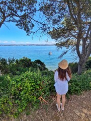 A girl gazes over the serene waters from a scenic island near Zadar, Croatia, with lush greenery and a calm sea