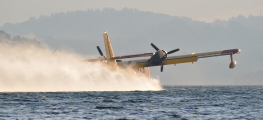 Seaplane moving in the water surface of a reservoir, firefighting plane filling water tanks