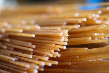A closeup portrait of a bunch of uncooked hard spaghetti sticks, ready to be cooked in boiling...