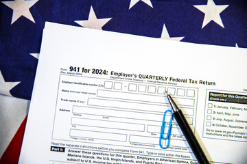 Employer's Quarterly Federal Tax Return form with pen and American flag in the backdrop