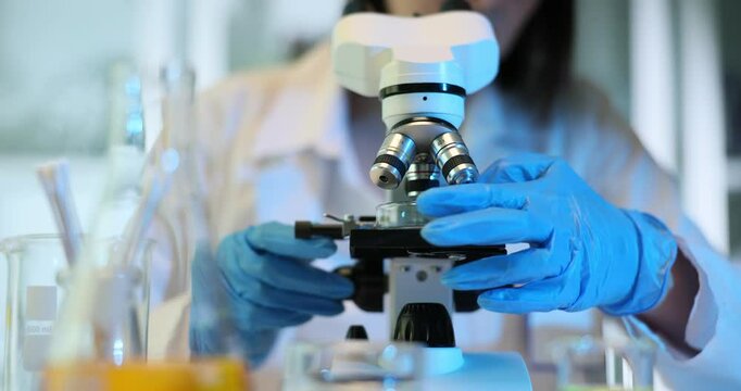 Scientist biologist virologist using microscope places petri dish for research in laboratory