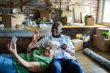 Senior couple video calling family while unpacking in new home