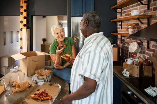 Senior couple eating pizza after moving into new home