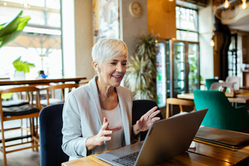 Senior businesswoman having video call on laptop in cafe