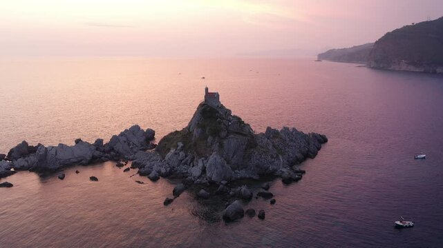 Flying drone 4K video around Sveta Nedjelja Island with magestic small church on cliff's top during evening sunset time hours. Balkans traveling, landmarks and Nature concept in Petrovac, Montenegro.