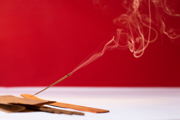 Fototapeta premium An incense stick smokes on a red background