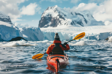 Solo kayaker paddling toward a majestic snow-covered mountain, navigating through icy polar waters with glaciers in the background on a clear, adventurous day