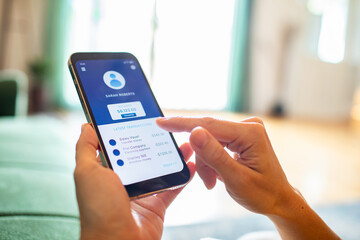 Close up of woman hands checking online banking app on smartphone