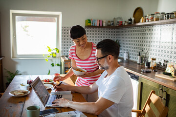 Couple reviewing documents together while using laptop at home