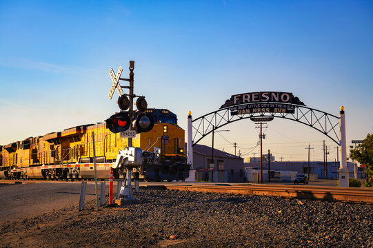 Fresno, California, USA - June 17, 2023 : Union Pacific train passing through Fresno, California, with the iconic welcome sign over Van Ness Avenue in the background.