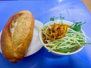 Dalat style pork meatball Banh Mi with dipping sauce including meatballs, shredded spinach and topped with stir-fried chili and fried onions