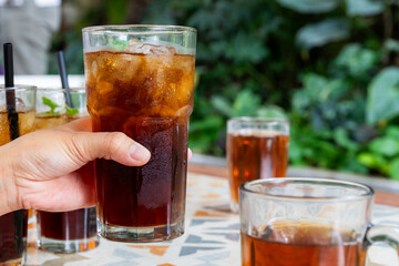 hand picking a glass of refreshing iced tea with ice cubes and mint leaves as a garnish