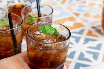 hand picking a glass of refreshing iced tea with ice cubes and mint leaves as a garnish