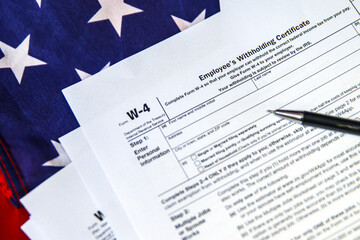 W4 Form Employee's Withholding Certificate with pen and American flag in the backdrop. Form for withholding tax, background
