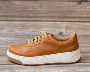 Casual style sneaker, light brown and white on a wooden background, right side