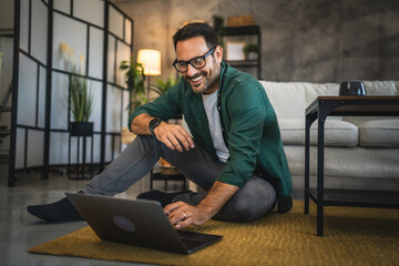 Adult man work from home on laptop seat on floor at home