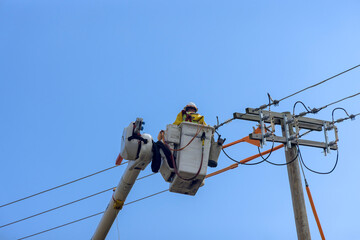 In order to maintain service at high voltage power line, an electrician officer uses insulated crane basket while working on climbing pole