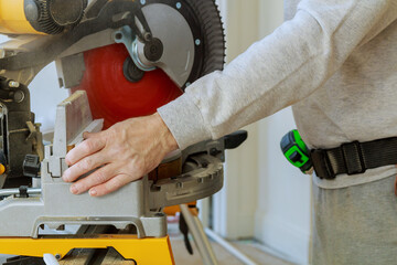 Using an electric circular saw at sawmill, professional carpenter cuts wood molding trim