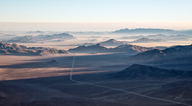 Aerial view of Isolated mountain ridges and the C27 gravel road at the edge of the Namib Desert. NamibRand Nature Reserve, Namibia.