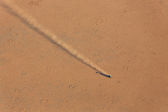 Aerial view of A vehicle of the balloon ground crew tries to follow the flight direction of the hot-air balloon, crossing a sandy plain at the edge of the Namib Desert, Namibia.
