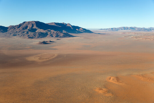 Aerial view of Arid desert plains and isolated mountain ridges at the edge of the Namib Desert. Namib Rand Nature Reserve, Namibia.