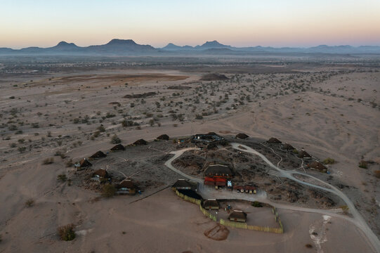 Aerial view of The Doro Nawas Camp and arid desert plains at the edge of the dry bed of the Aba-Huab river, at dawn, Damaraland, Kunene Region, Namibia.
