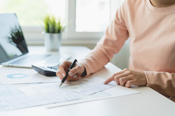 Deduction planning, debt asian young woman hand using calculator to calculating money balance from bill and income, cost budget expenses for pay money form personal individual on table at home.