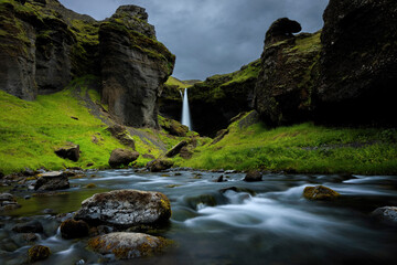 View of Kvernufoss waterfall surrounded by majestic rocks and greenery in a beautiful canyon, Skogafoss, Iceland.