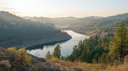 Obraz premium An expansive view of a hydroelectric reservoir surrounded by forests and hills, with the dam barely visible in the distance.