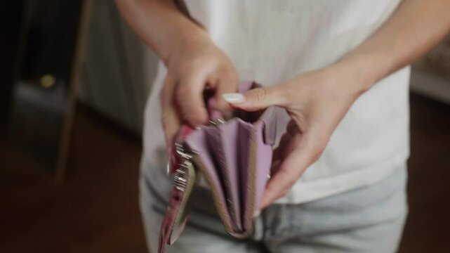 Woman shows an empty blue wallet, revealing a lack of money inside. The scene highlights financial struggles and the challenges of managing personal finances