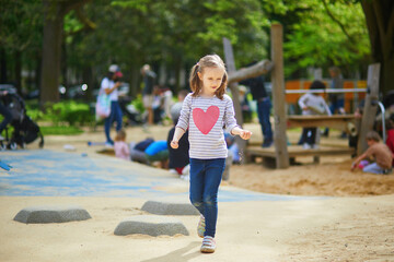 Adorable preschooler girl on playground on a sunny day. Preschooler child playing outdoors. Outdoor activities for kids.