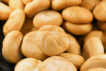 Fresh Kaiser rolls stacked on a store shelf. Group of classic bread rolls on display. Bakery section with a pile of golden brown buns. Perfect for sandwiches or breakfast. Crisp, freshly baked roll.
